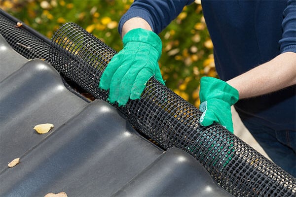 worker installing black mesh gutter screens